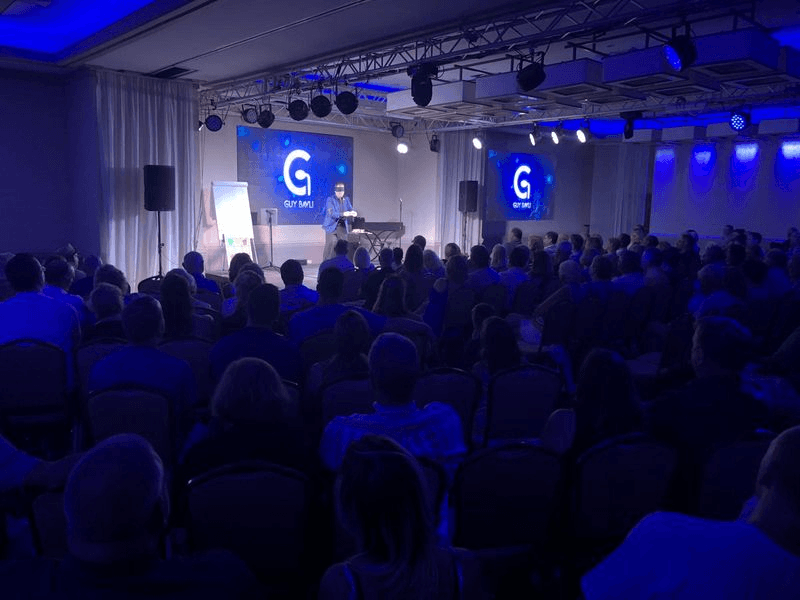 A full corporate audience watching Guy Bavli on the main stage